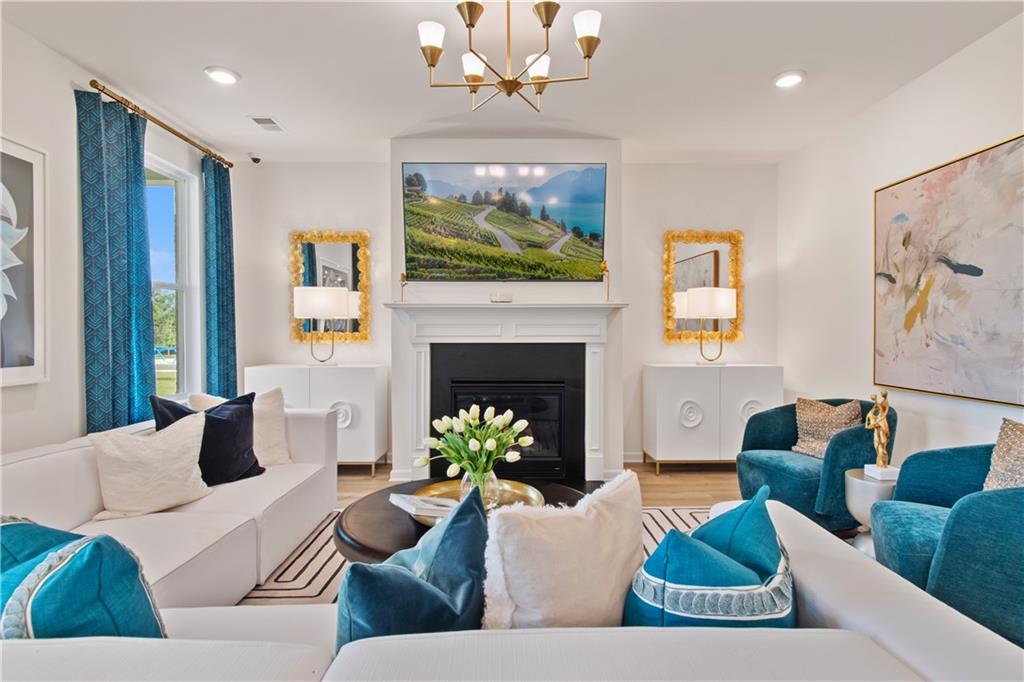 295 Abbotts Xing Circle Covington, GA 30016 - Photo 9 of 34 a living room with furniture a fireplace and a chandelier