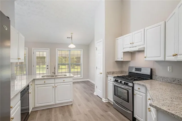 a kitchen with granite countertop a sink cabinets stainless steel appliances and a window