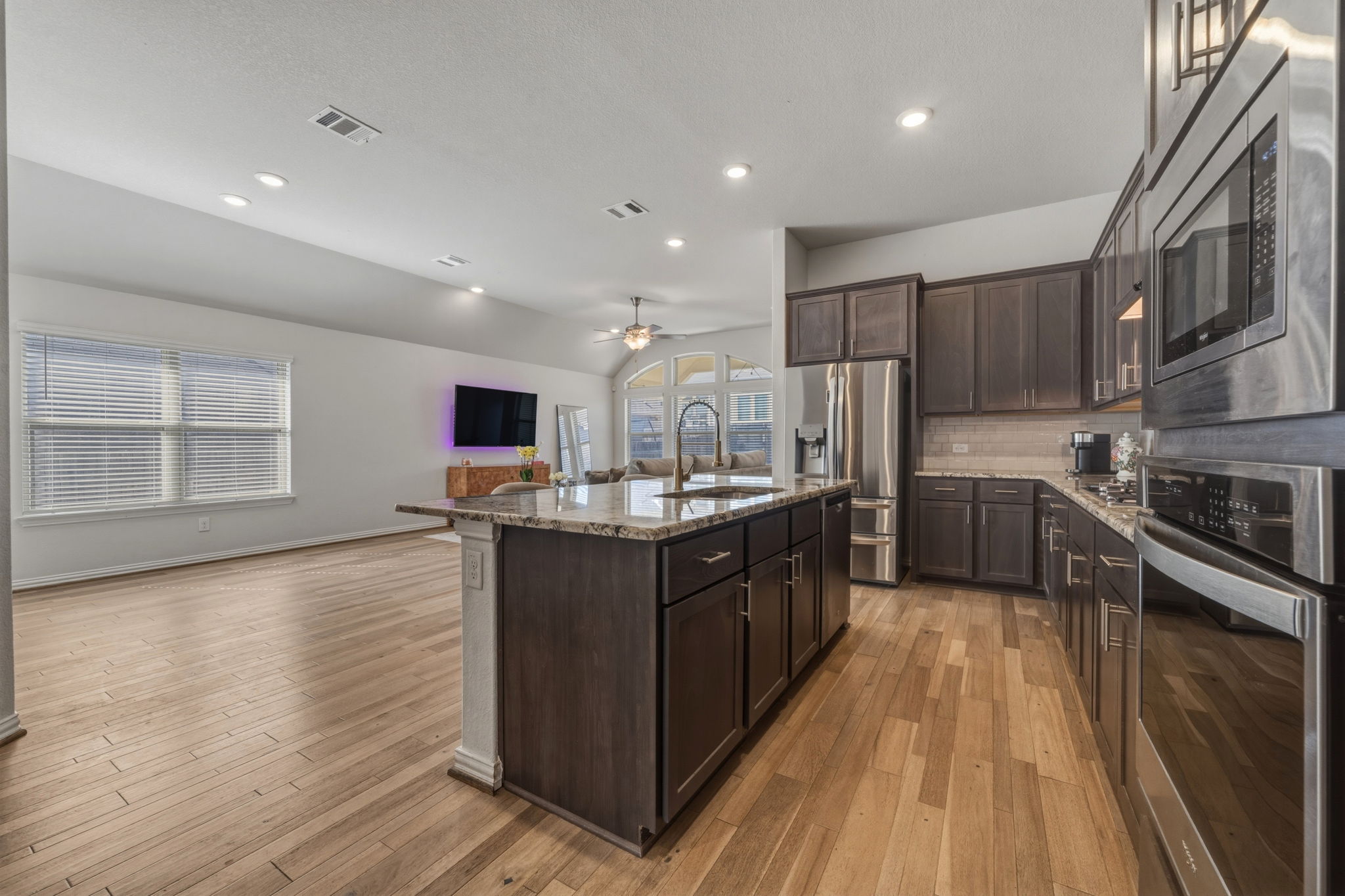 918 Leadtree Loop Buda, TX 78610 - Photo 26 of 27 Kitchen with light stone counters, dark wood finish cabinetry, stainless steel appliances, open floor plan, and ceiling fan