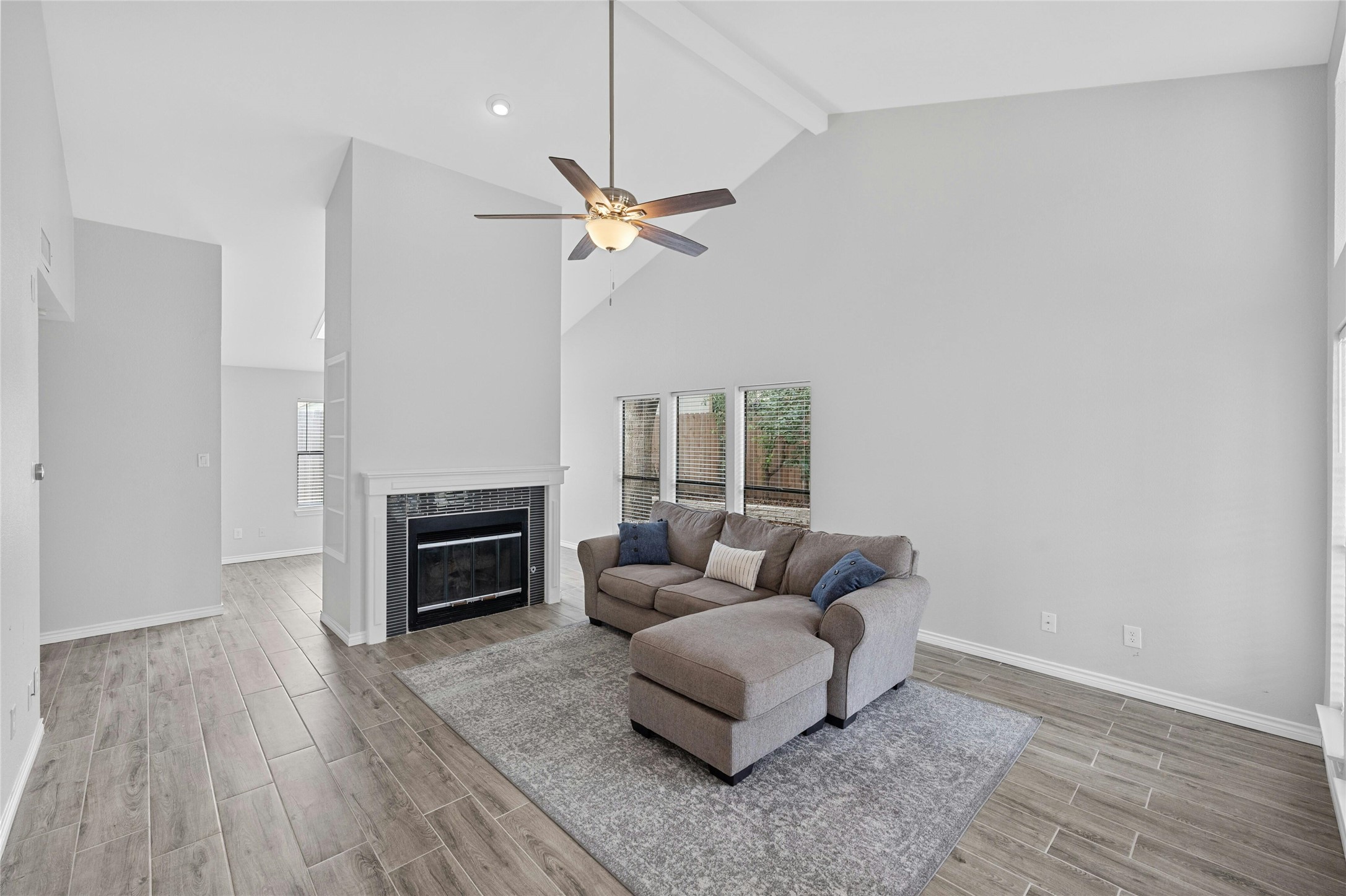 8303 Los Ranchos Drive Austin, TX 78749 - Photo 4 of 26 Living area with wood finish floors, a tiled fireplace, vaulted ceiling, and a ceiling fan
