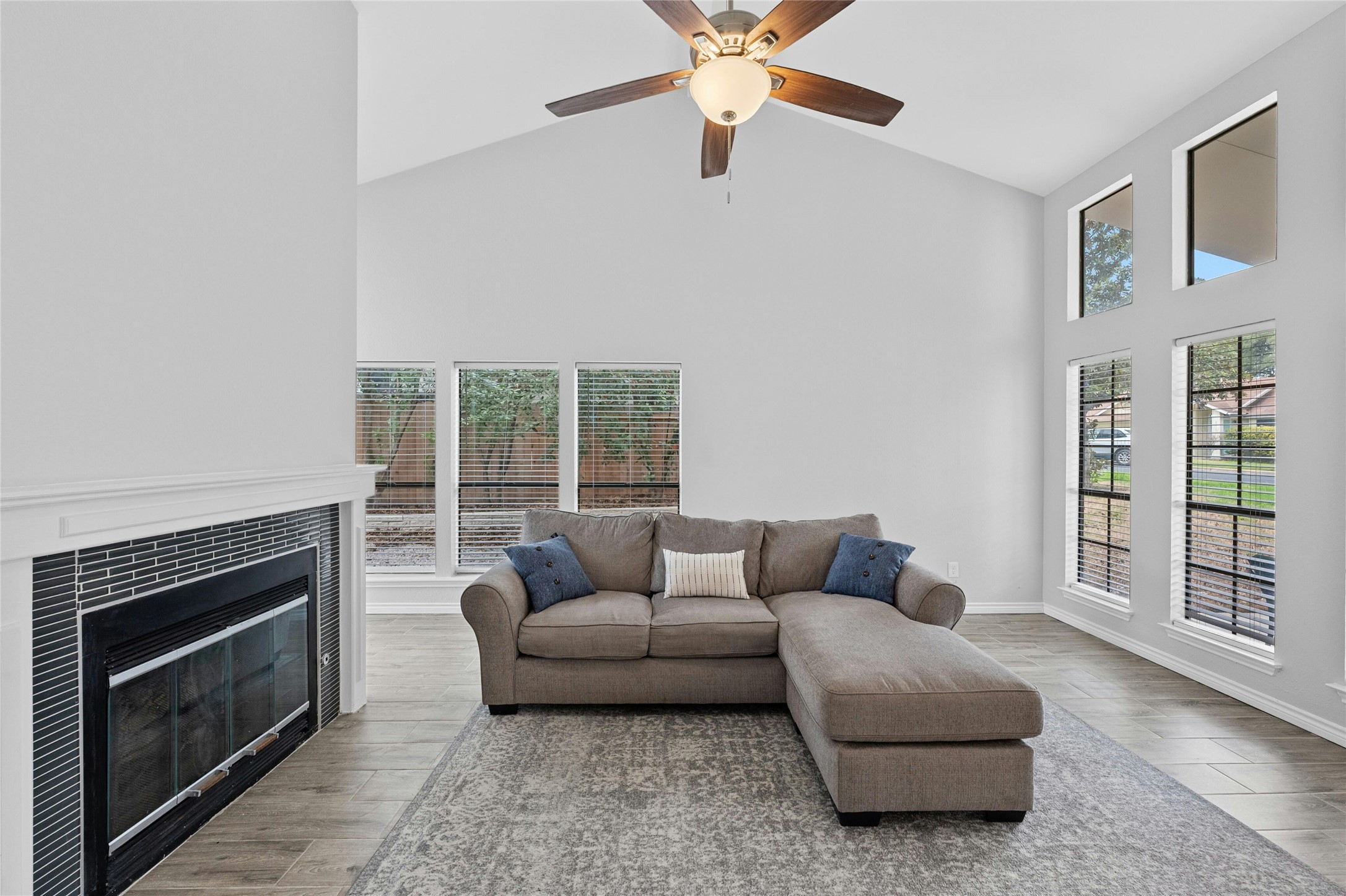 8303 Los Ranchos Drive Austin, TX 78749 - Photo 6 of 26 Living room featuring lofted ceiling, a tile fireplace, light wood-style floors, and ceiling fan