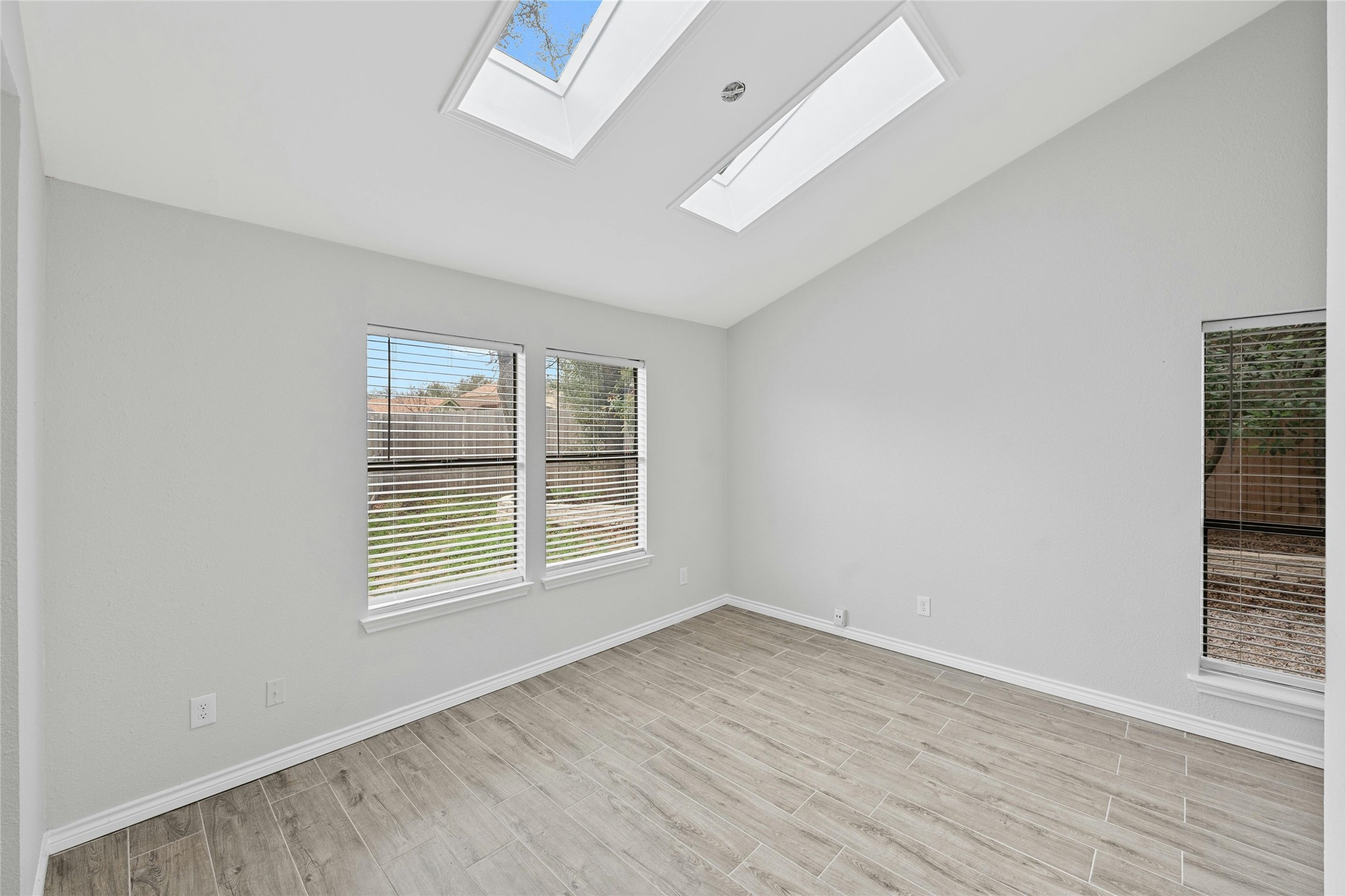8303 Los Ranchos Drive Austin, TX 78749 - Photo 8 of 26 Empty room with wood tiled floors, lofted ceiling, and a skylight