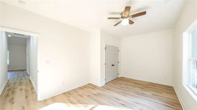 an empty room with wooden floor and ceiling fan