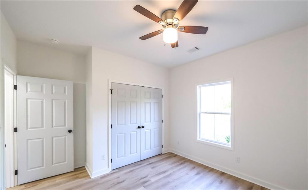 128 Pollard Road Temple, GA 30179 - Photo 34 of 36 an empty room with wooden floor ceiling fan and windows
