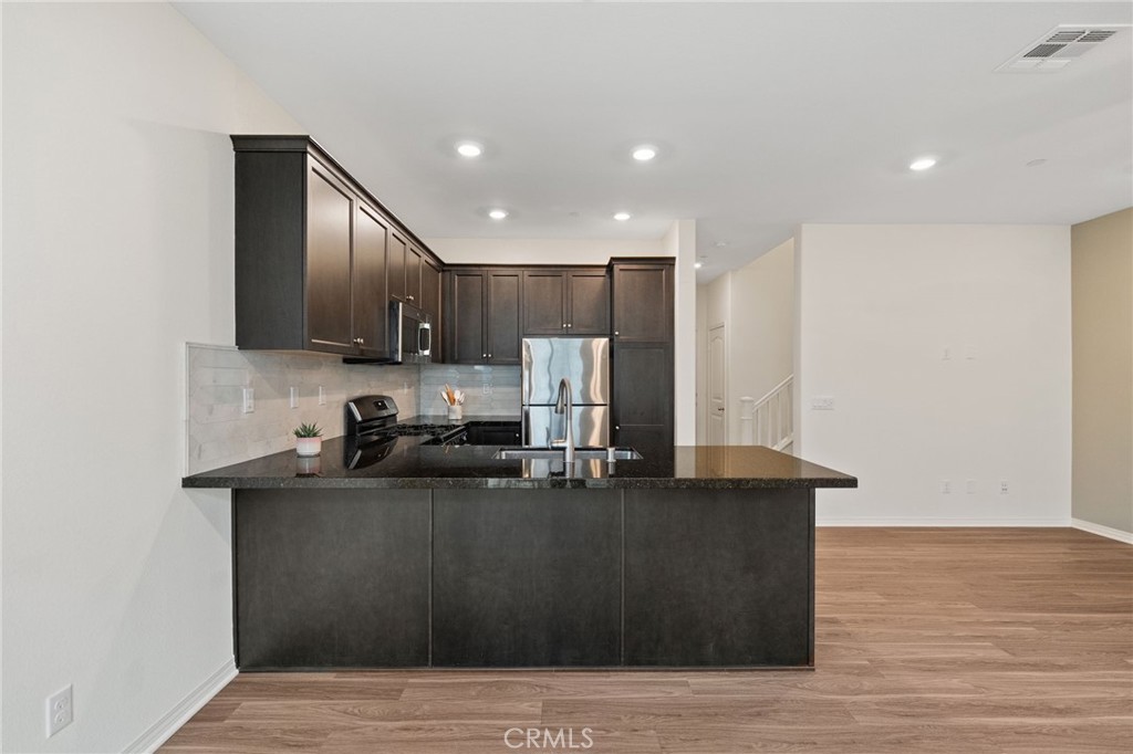41979 Rondo Street, Unit 1106 Murrieta, CA 92562 - Photo 7 of 18 a kitchen with kitchen island granite countertop a sink cabinets and wooden floor