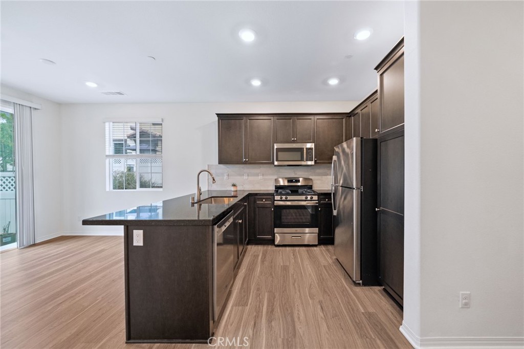 41979 Rondo Street, Unit 1106 Murrieta, CA 92562 - Photo 8 of 18 a kitchen with kitchen island granite countertop a refrigerator stove top oven and sink