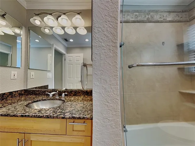 a bathroom with a granite countertop sink a mirror and shower