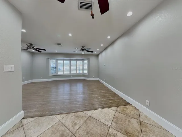 an empty room with windows and ceiling fan