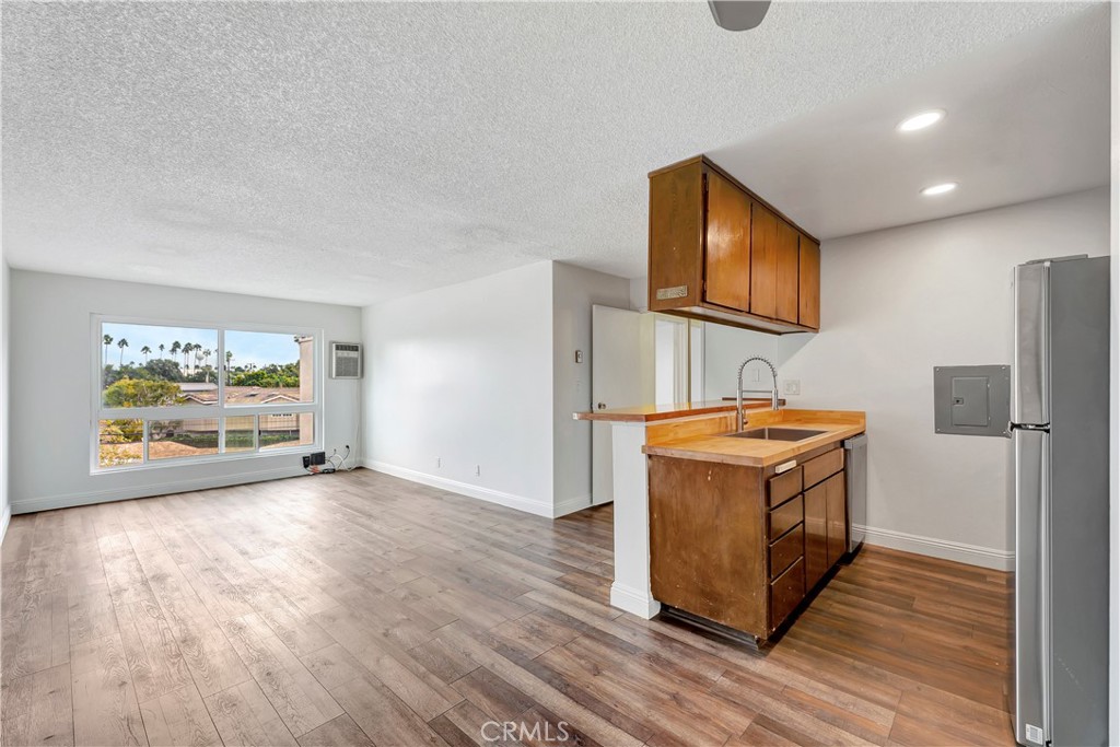 5585 Pacific Coast Highway, Unit 342 Long Beach, CA 90804 - Photo 4 of 32 a view of a kitchen with stainless steel appliances wooden floor and chair