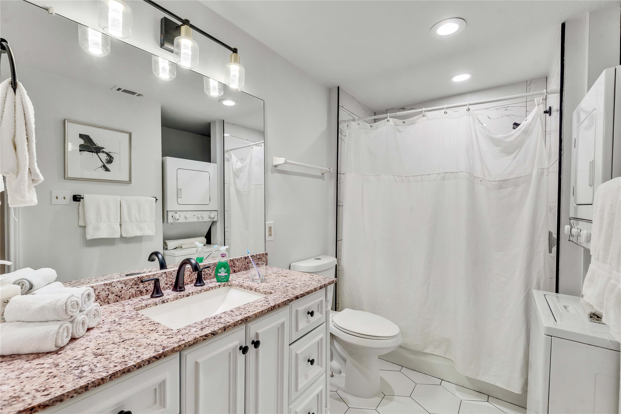 2529 Rio Grande Street, Unit 56 Austin, TX 78705 - Photo 15 of 16 Bathroom with toilet, stacked washing maching and dryer, visible vents, tile patterned flooring, and vanity