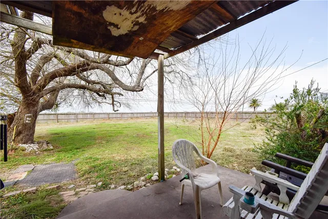 a view of a patio with chair and table under an umbrella