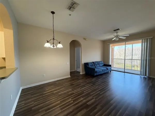 a view of a room with wooden floor chandelier and windows