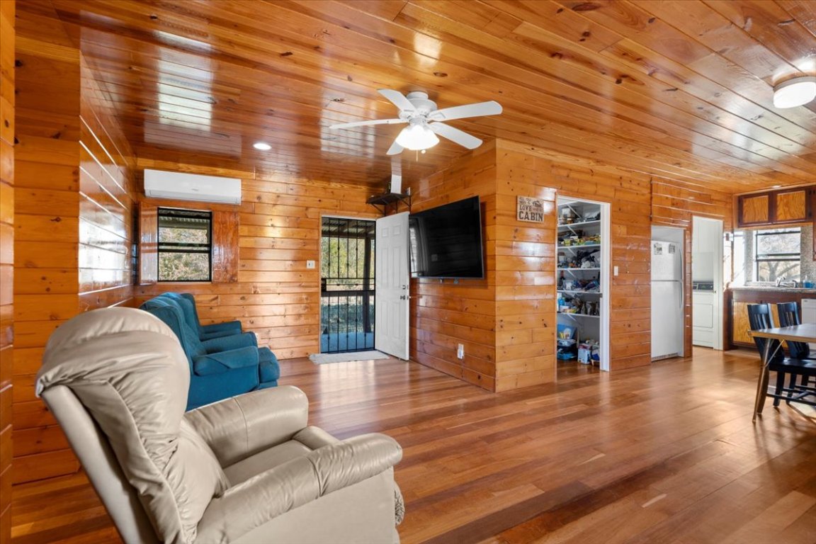 4339 Pettytown Road Dale, TX 78616 - Photo 14 of 33 Living room with plenty of natural light, wood finished floors, wooden walls, wooden ceiling, and a ceiling fan