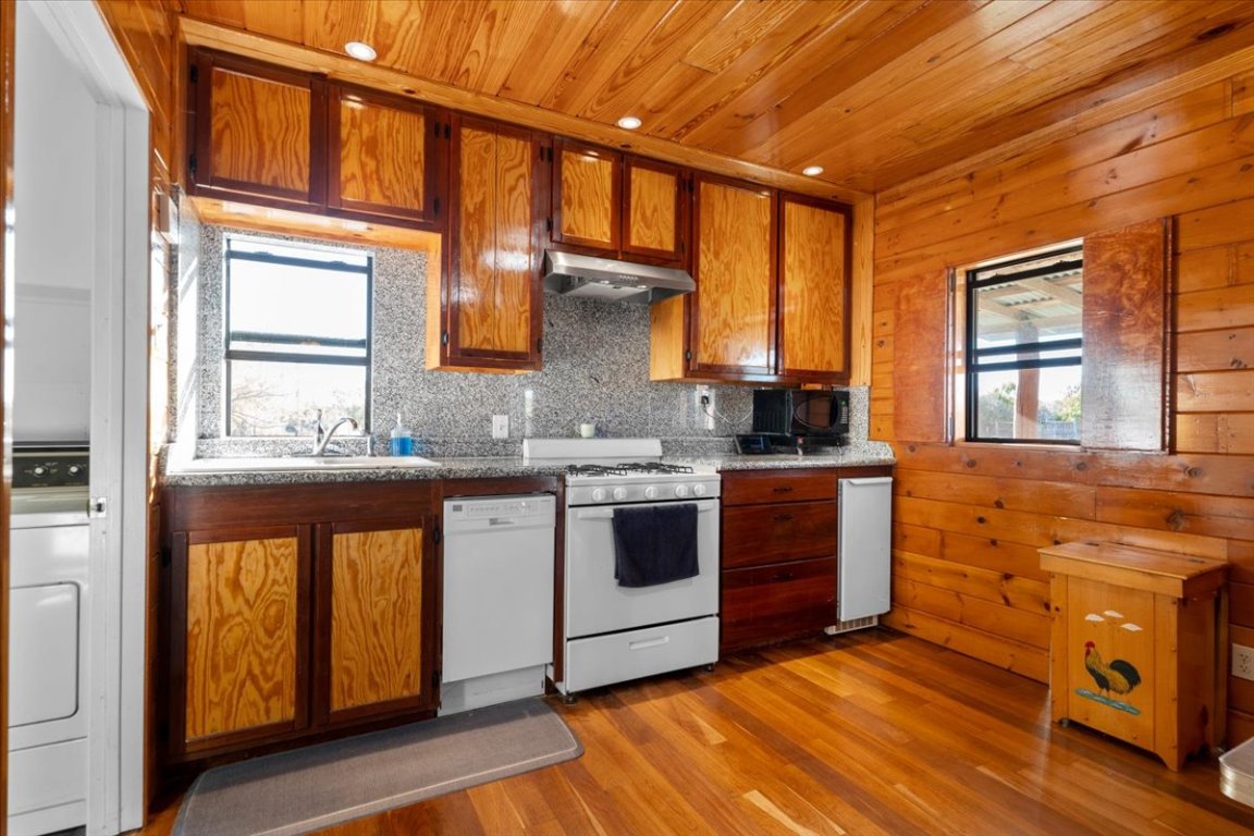 4339 Pettytown Road Dale, TX 78616 - Photo 16 of 33 Kitchen with light wood-style floors, brown cabinetry, white appliances, washer / clothes dryer, and wooden ceiling