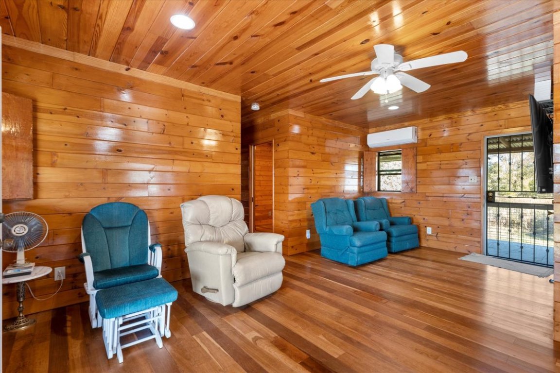 4339 Pettytown Road Dale, TX 78616 - Photo 7 of 33 Living area featuring wood finished floors, wood ceiling, wood walls, a ceiling fan, and a wall unit AC