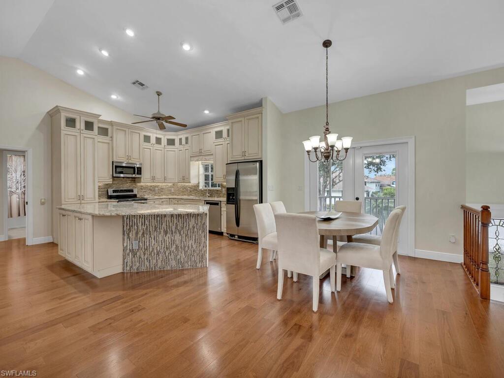 558 Corbel Drive Naples, FL 34110 - Photo 8 of 22 a view of a dining room and livingroom with furniture wooden floor a chandelier