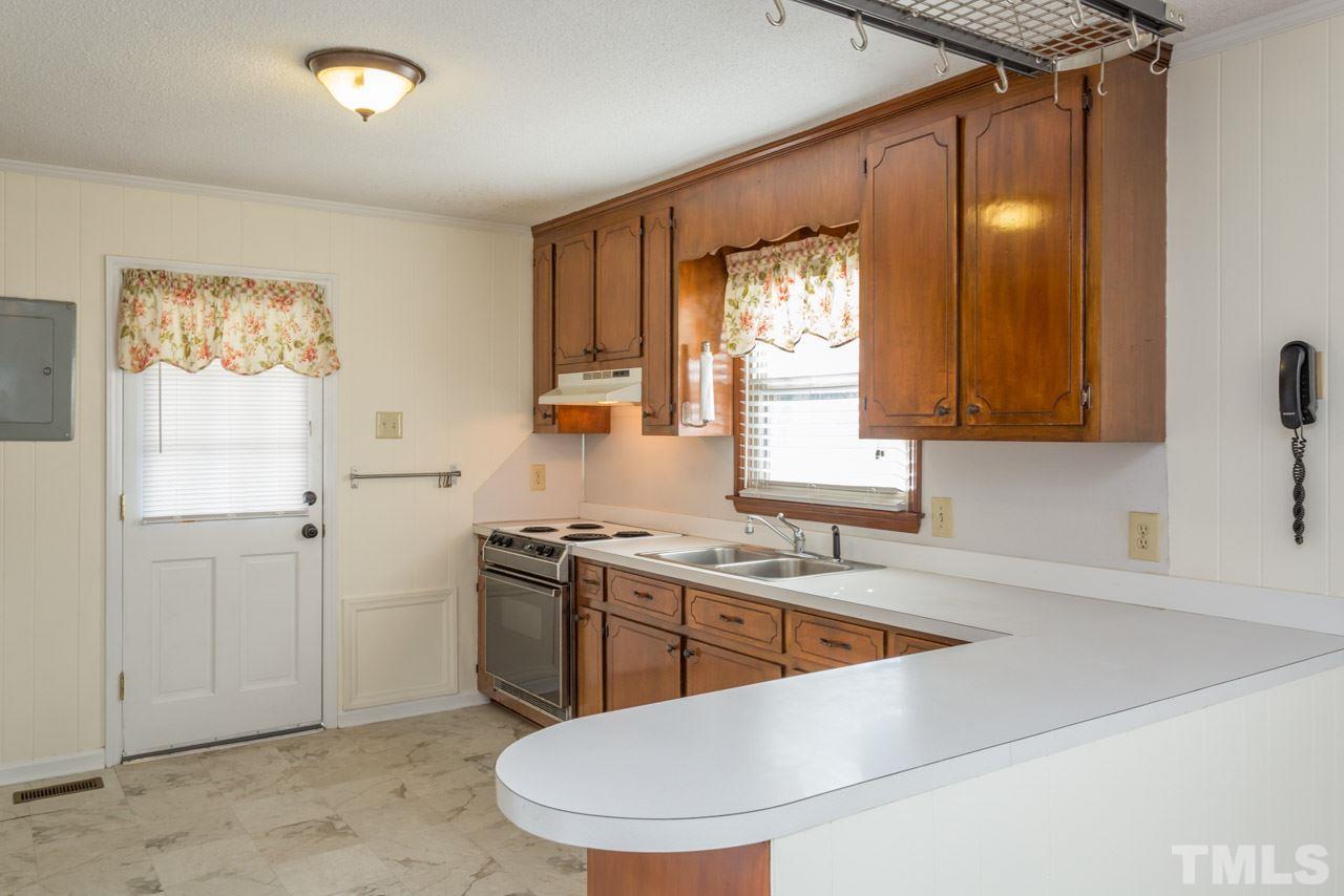 5405 Cheek Road Durham, NC 27704 - Photo 9 of 24 a kitchen with stainless steel appliances granite countertop a sink a stove a refrigerator a washer dryer and white cabinets