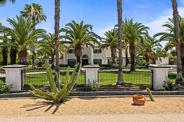 a view of a house with a yard and coconut trees