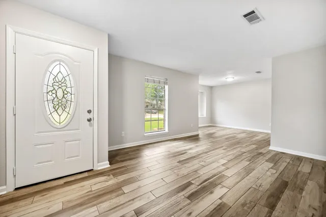 a view of empty room with window and wooden floor