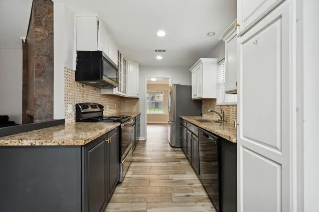 a kitchen with stainless steel appliances granite countertop a refrigerator a stove top oven a sink and dishwasher
