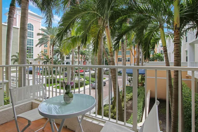 a balcony with table and chairs potted plants and palm tree