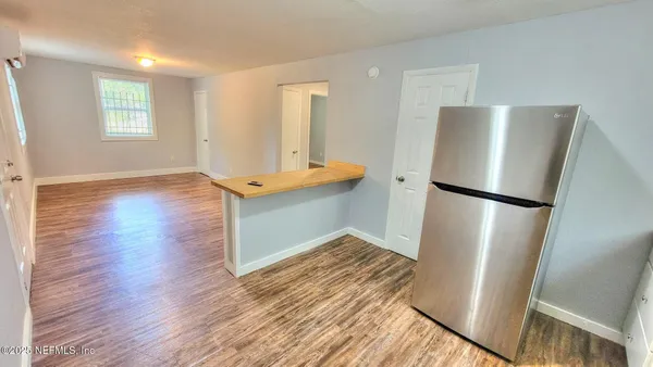 an empty room with wooden floor and a kitchen