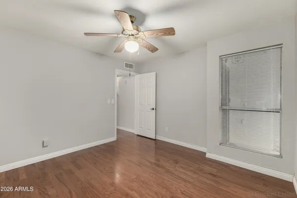 an empty room with wooden floor closet and fan