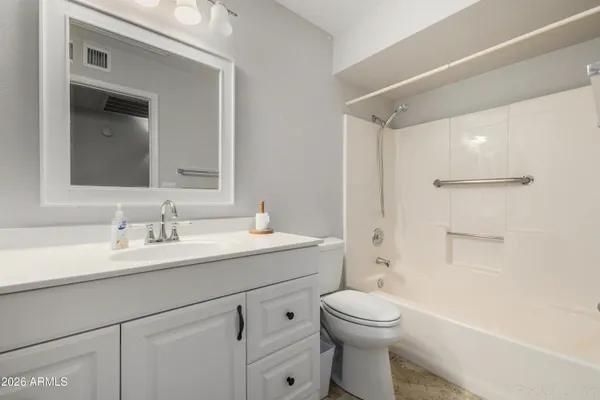 a bathroom with a toilet a sink a mirror a shower a vanity and window