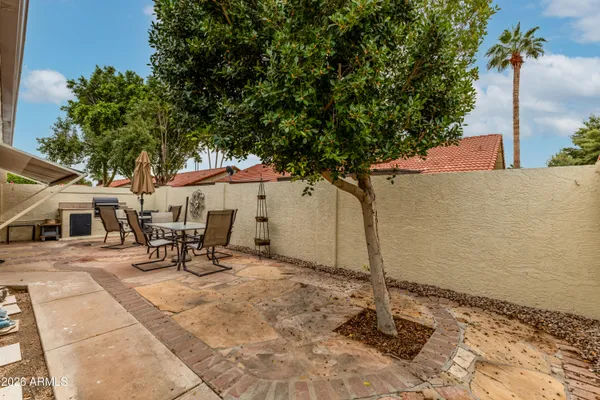 a view of a backyard with table and chairs and a large tree