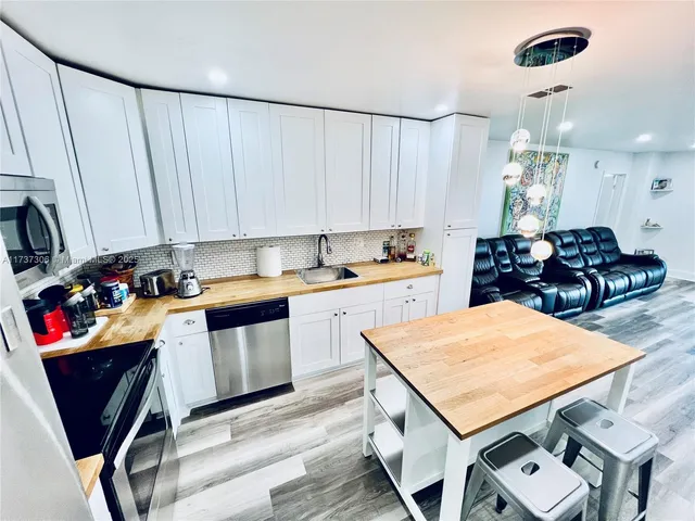 a kitchen with stainless steel appliances kitchen island granite countertop a table chairs in it and white cabinets
