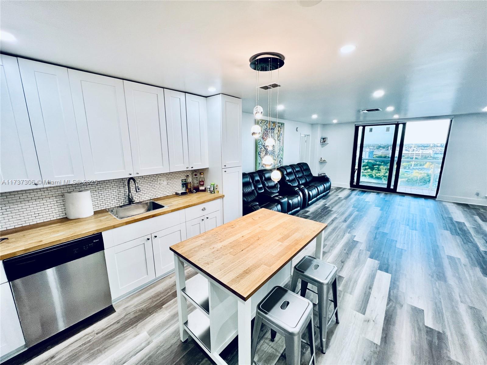 13499 Biscayne Boulevard, Unit PH1705 North Miami, FL 33181 - Photo 14 of 37 a kitchen with a table chairs sink and cabinets