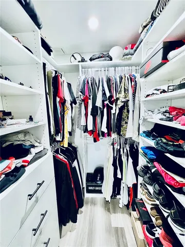 a view of walk in closet with clothes and shoes