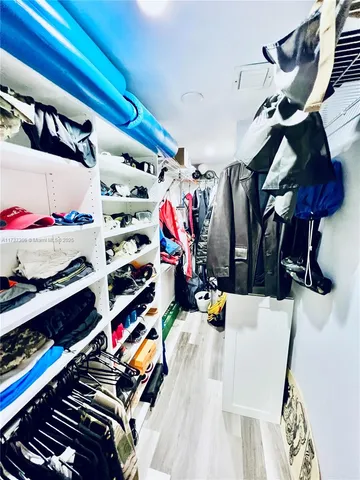a view of walk in closet with clothes and shoes