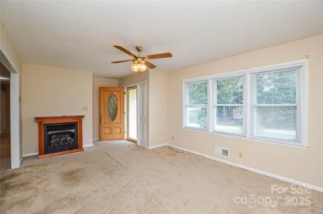 an empty room with windows and fireplace