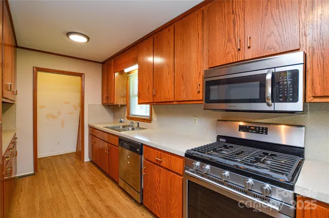 a kitchen with granite countertop wooden cabinets stainless steel appliances and wooden floor