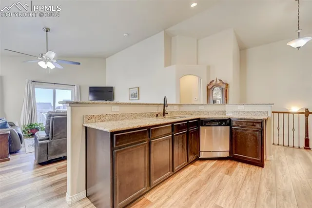 a kitchen with stainless steel appliances granite countertop a sink a stove a refrigerator and a dining table with wooden floor