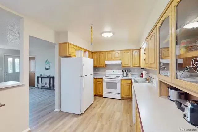 a kitchen with refrigerator a stove and wooden floor