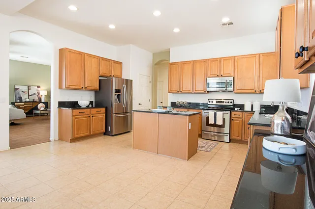 a kitchen with stainless steel appliances a stove a sink a oven a dining table and chairs