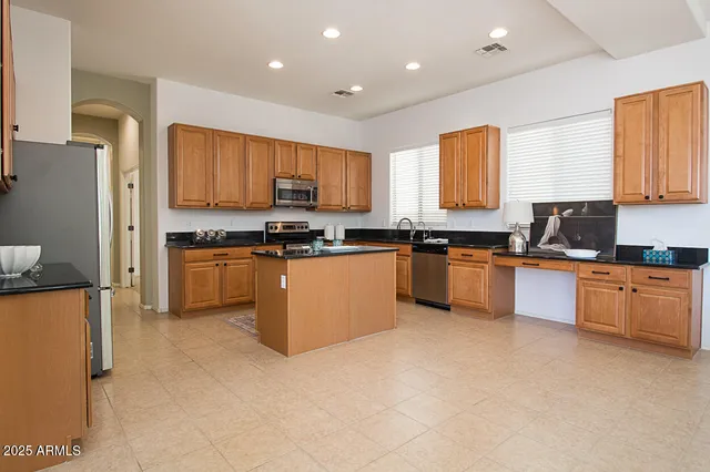 a kitchen with stainless steel appliances a sink a stove a refrigerator cabinets and a window