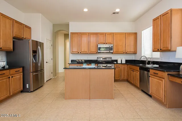 a kitchen with stainless steel appliances granite countertop a stove top oven a refrigerator a sink and dishwasher