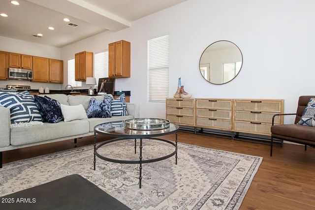 a living room with furniture a rug kitchen view and a table