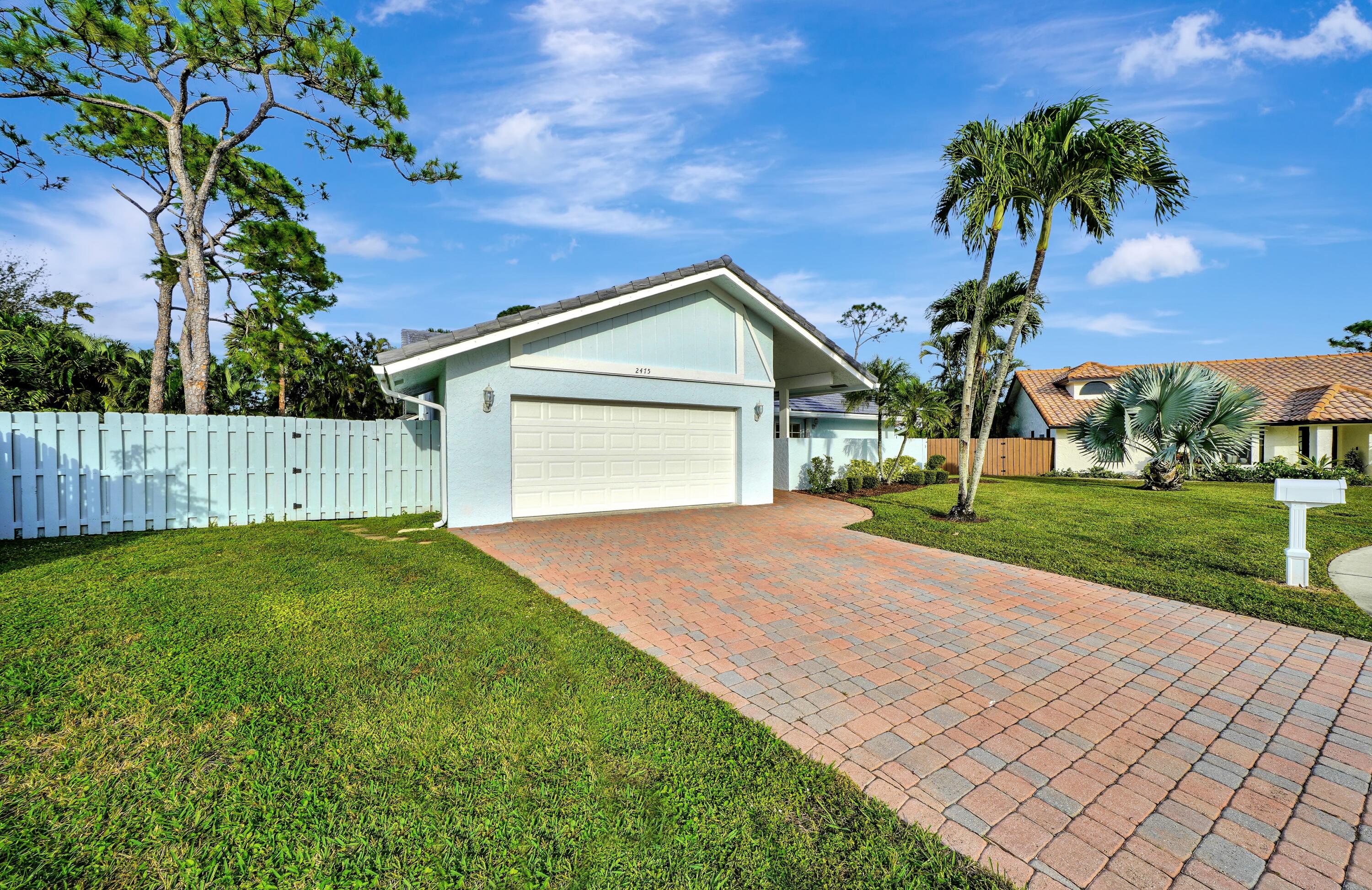 2475 Northwest 25th Street Boca Raton, FL 33431 - Photo 17 of 72 a front view of a house with a yard and garage
