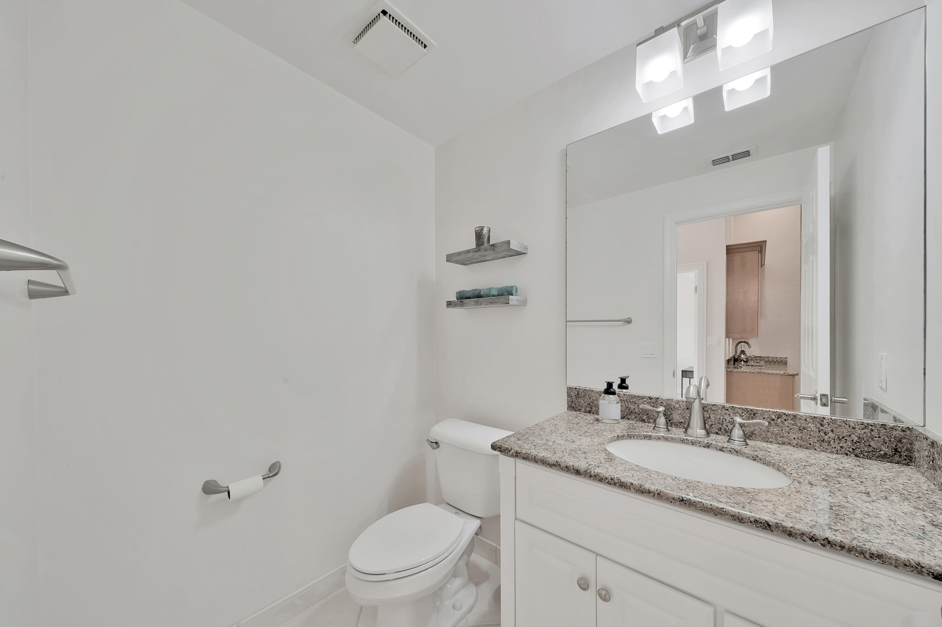 2475 Northwest 25th Street Boca Raton, FL 33431 - Photo 22 of 72 a bathroom with a granite countertop sink a toilet and a mirror