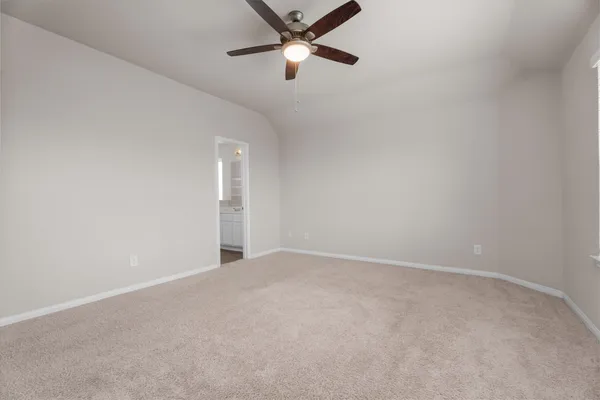 an empty room with ceiling fan and windows