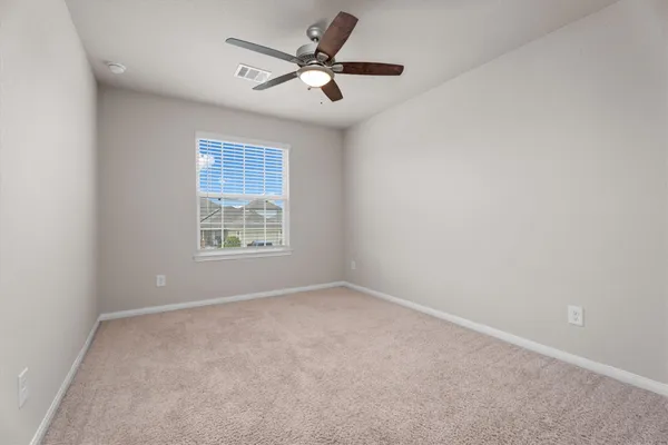 an empty room with a window and a fan
