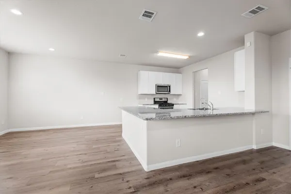 a kitchen with stainless steel appliances granite countertop a sink a stove and a wooden floors