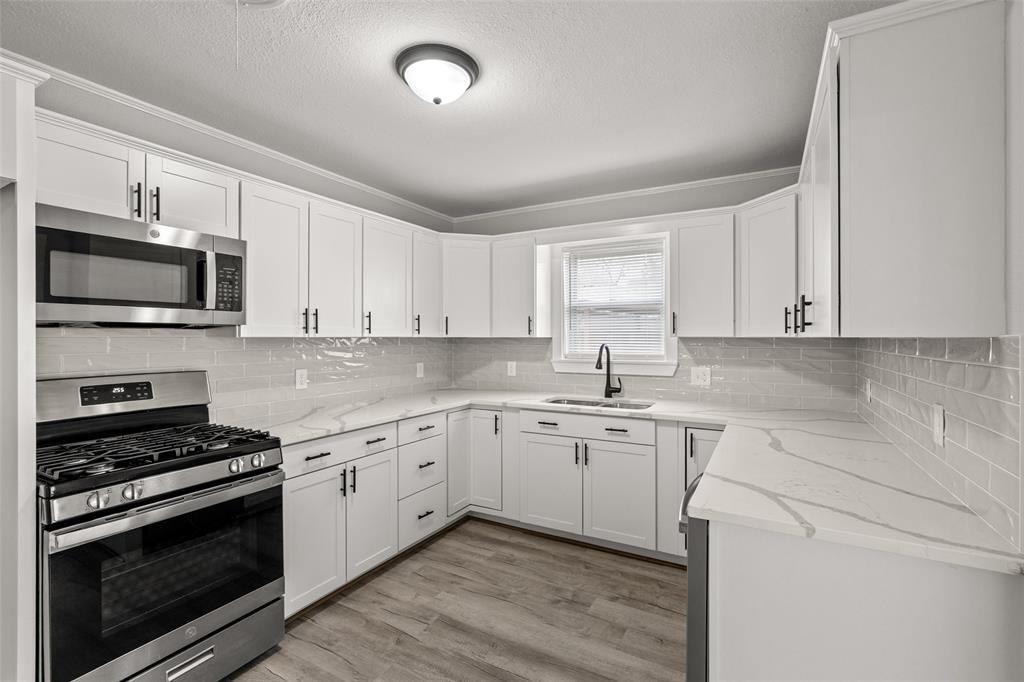 1506 West Main Street Denison, TX 75020 - Photo 11 of 38 a kitchen with a sink stove and microwave