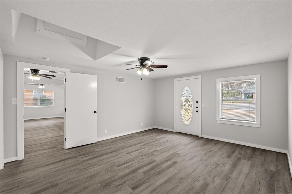 1506 West Main Street Denison, TX 75020 - Photo 25 of 38 an empty room with wooden floor chandelier fan and windows
