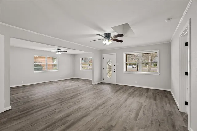 a view of an empty room with a window and wooden floor
