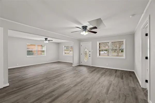 a view of an empty room with a window and wooden floor